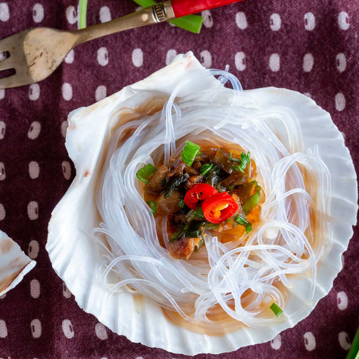 Top down shot showing the juicy scallops on the half shell topped with garlic sauce in the shell.