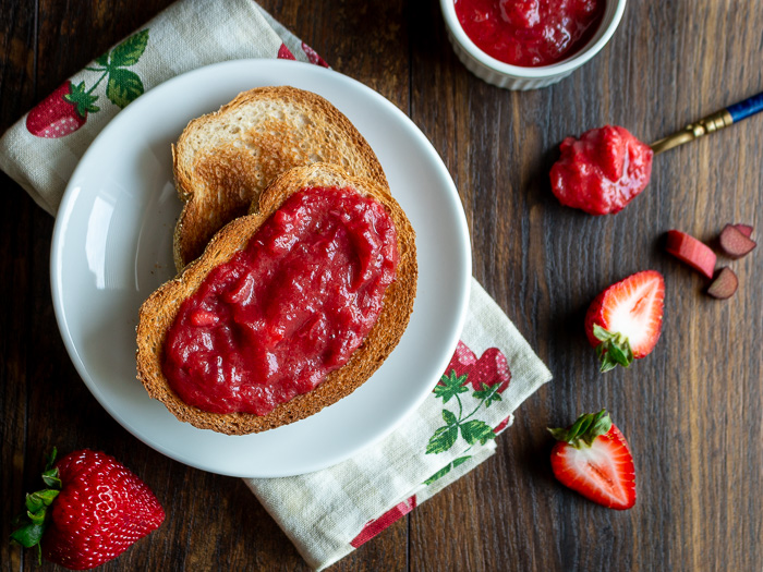 2 slices of toast with a jam swirl and a spoon of jam on the side