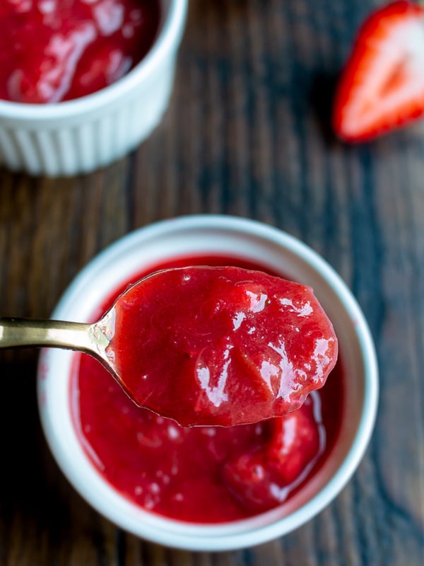 Spoonful of Strawberry Rhubarb refrigerator Jam over a white bowl.