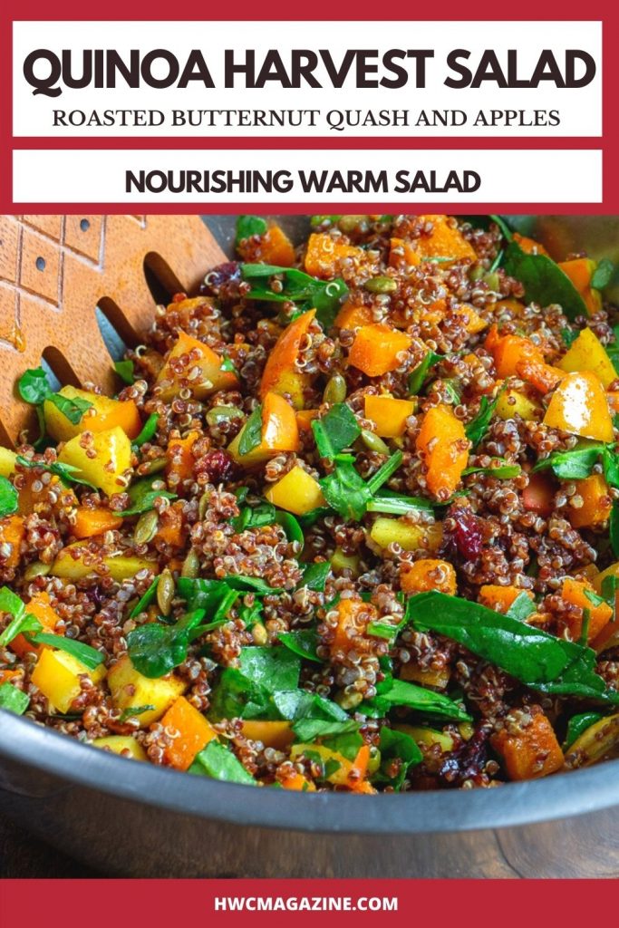 Quinoa Harvest salad getting tossed with wooden spoons in a big silver bowl.