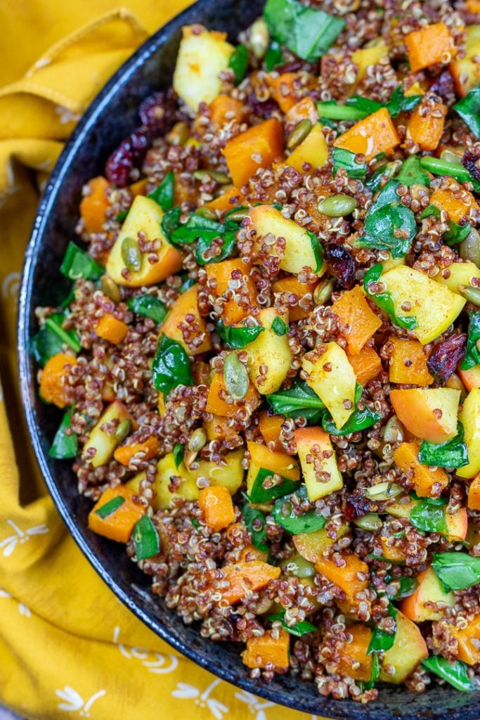 Top down shot of beautiful turmeric golden quinoa salad in a black plate.