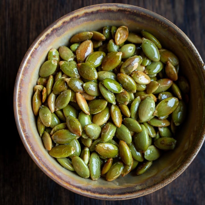 Roasted pepitas in a beige bowl.