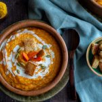 Top down photo of roasted butternut and carrot ginger soup with a side of homemade gluten-free croutons.