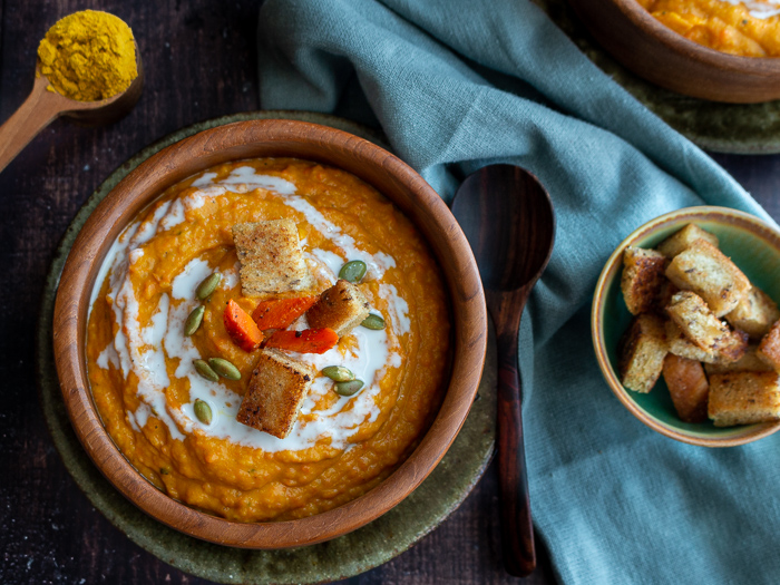 Top down photo of roasted butternut and carrot ginger soup with a side of homemade gluten-free croutons.