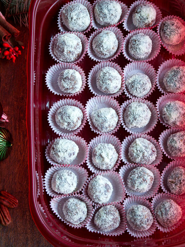 A huge tray of no bake protein balls dusted in ground almonds in a red Tupperware. 