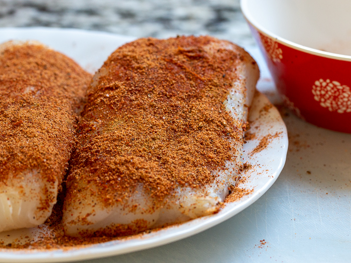 Cod fish seasoned with cajun seasoning ready to be pan fried. 