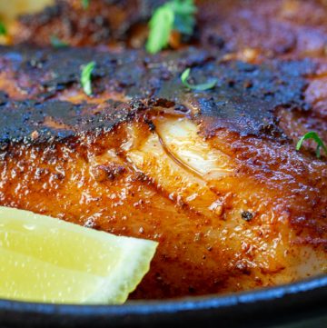 Close up shot of flaky cajun cod with a wedge of lemon.