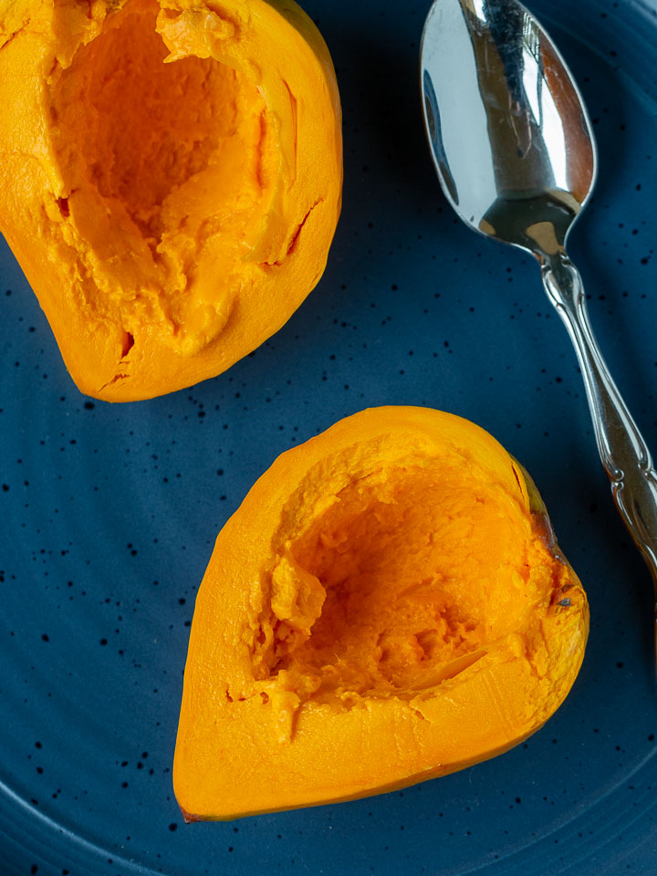 Fresh yellow sapote cut in half on a blue plate.