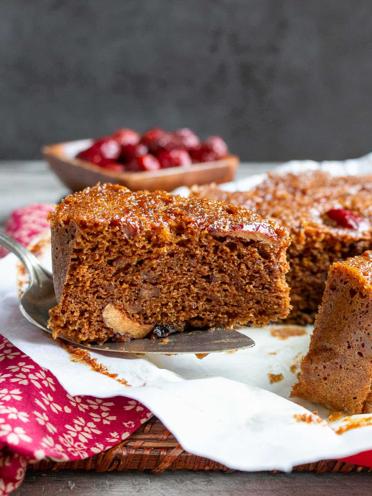 Slice of steamed gingerbread cooked via the microwave steam method getting placed on a white plate. 