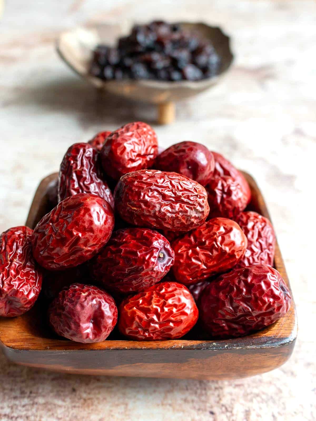 Dried Chinese red dates or you may know them as jujubes in a wooden bowl.