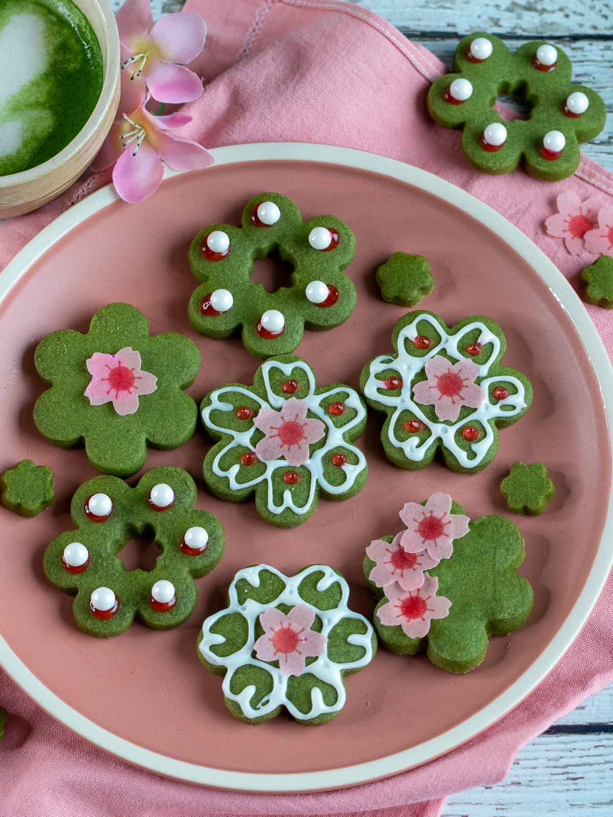 Top down shot of cherry blossom cookies on a pink plate decorated.