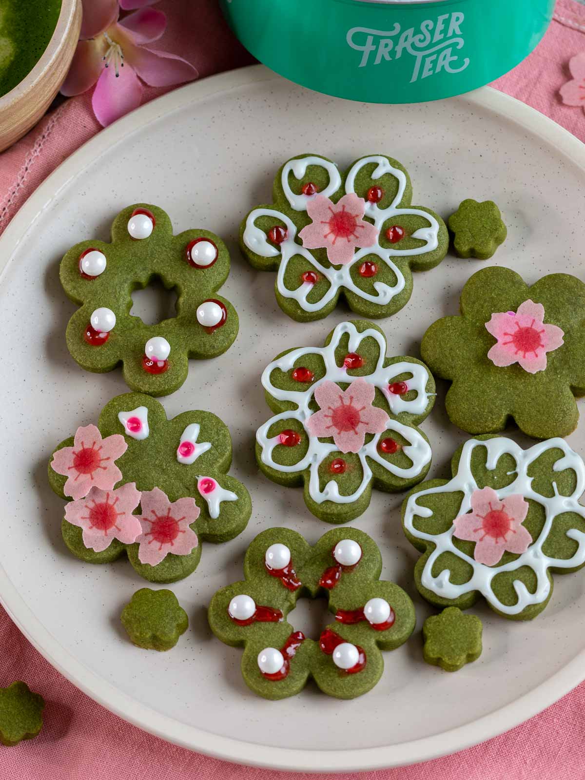 Decorated matcha cookies on a white plate with super cute cherry blossom edible decorations.