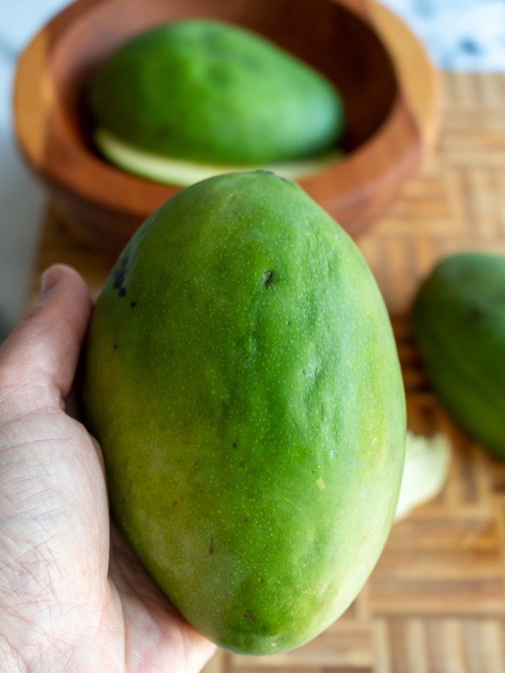 Bright green mango held in a hand. 