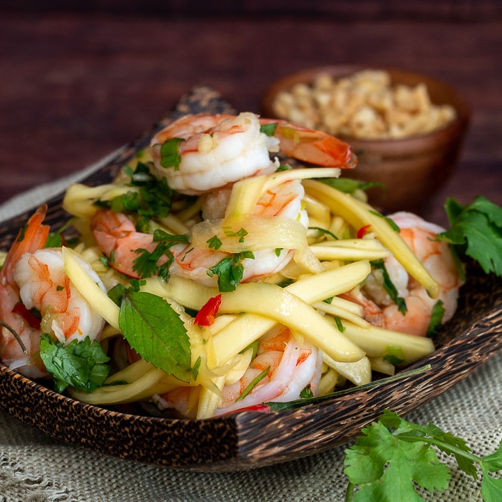 Thai Shrimp Green Mango Salad on a wooden plate.