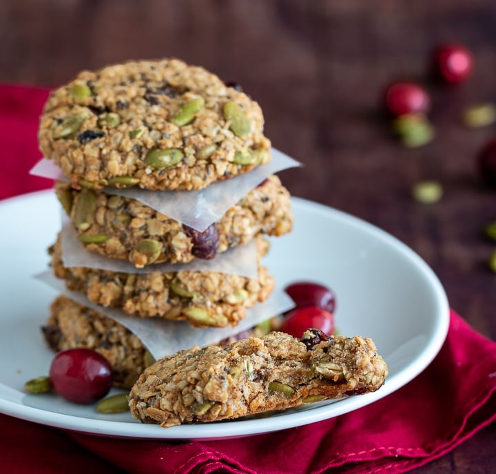 Four Breakfast cookie stacked on a white plate with one with a large bite taken out of it.