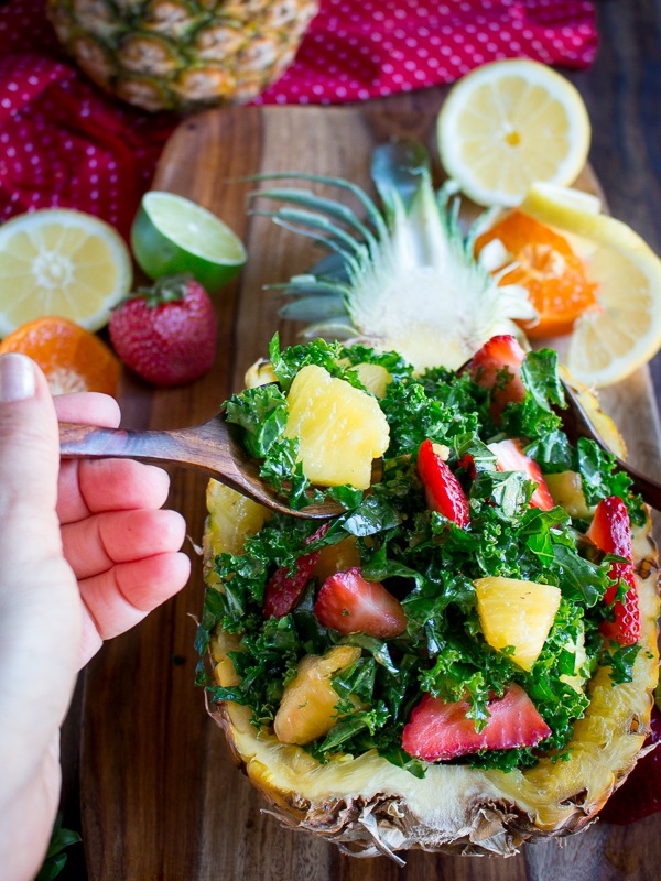 The bite shot with a pineapple and kale in a wooden spoon.