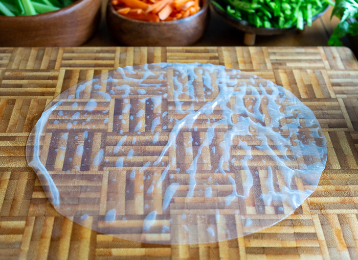 Rice paper wrapper moistened and on a cutting board.