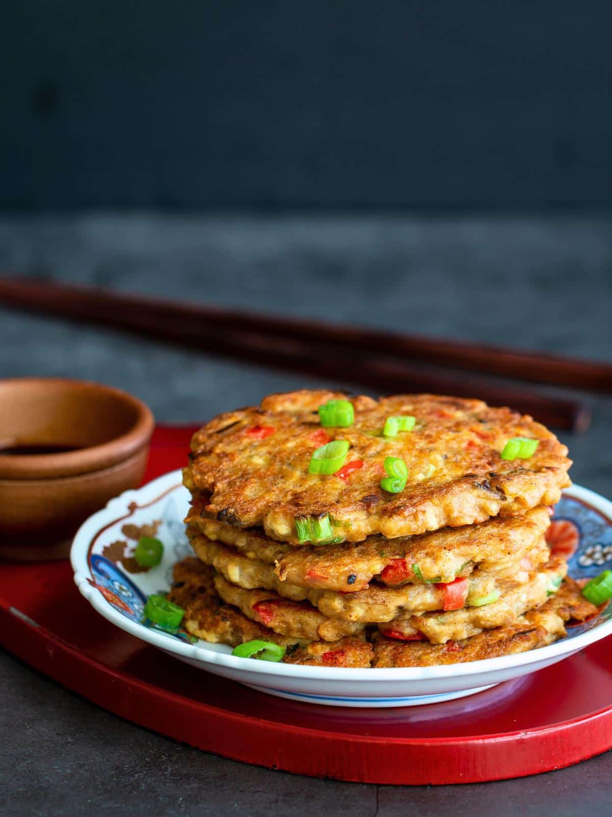 Savory gluten free flapjacks on a white plate with dipping sauce and chopsticks. 