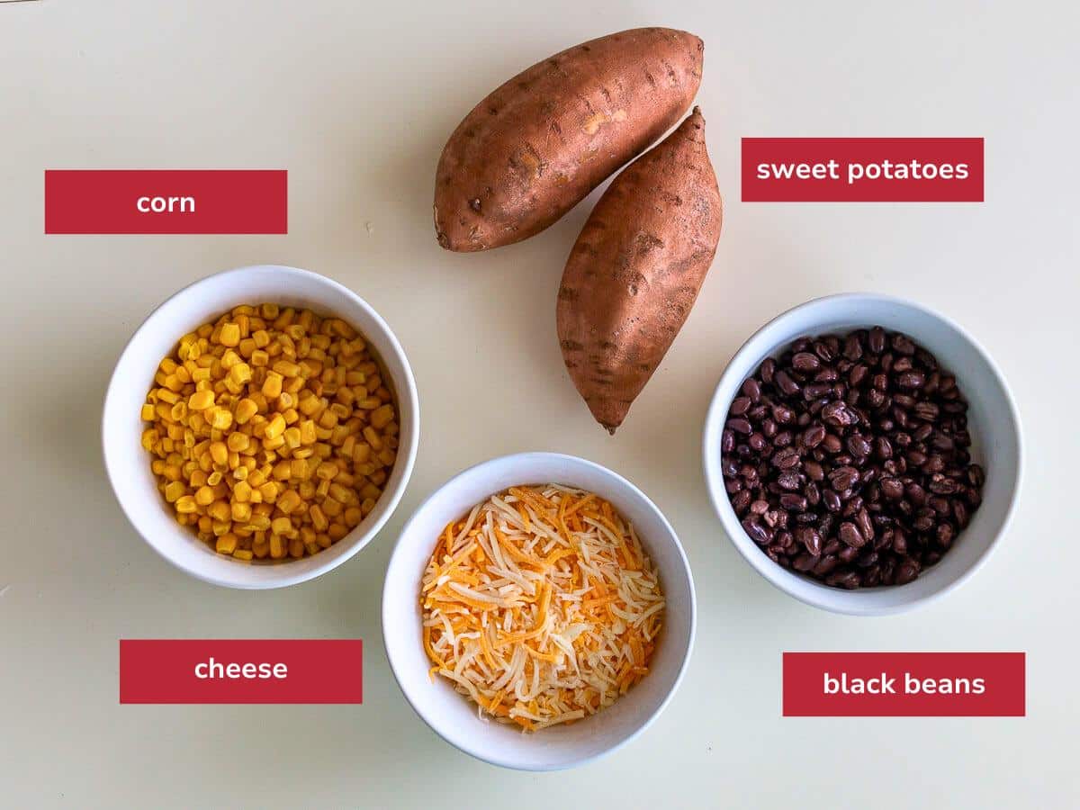 Vegetarian ingredients for filling such as sweet potatoes, black beans and corn laid out on a beige table. 