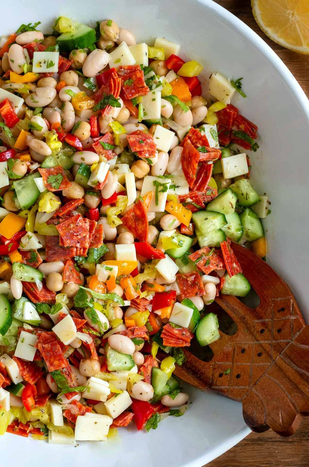 Summery bean salad with fresh vegetables, cold cuts, cheese and pepperoncini peppers. 