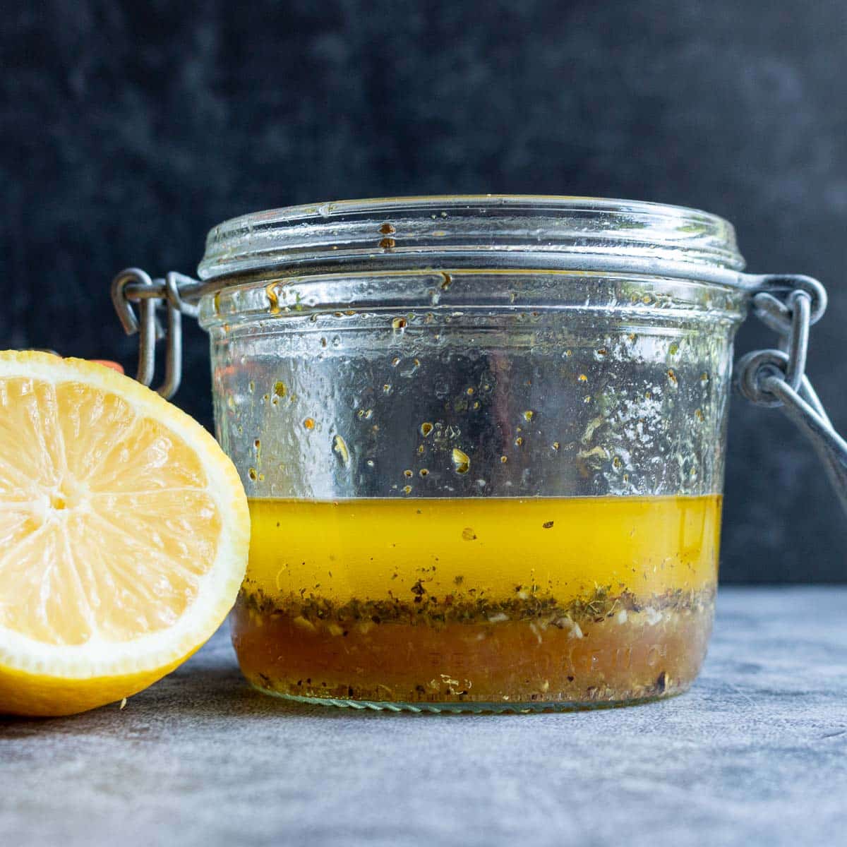 Lemon and White balsamic vinaigrette dressing in a jar with a lid with a fresh lemon next to it. 