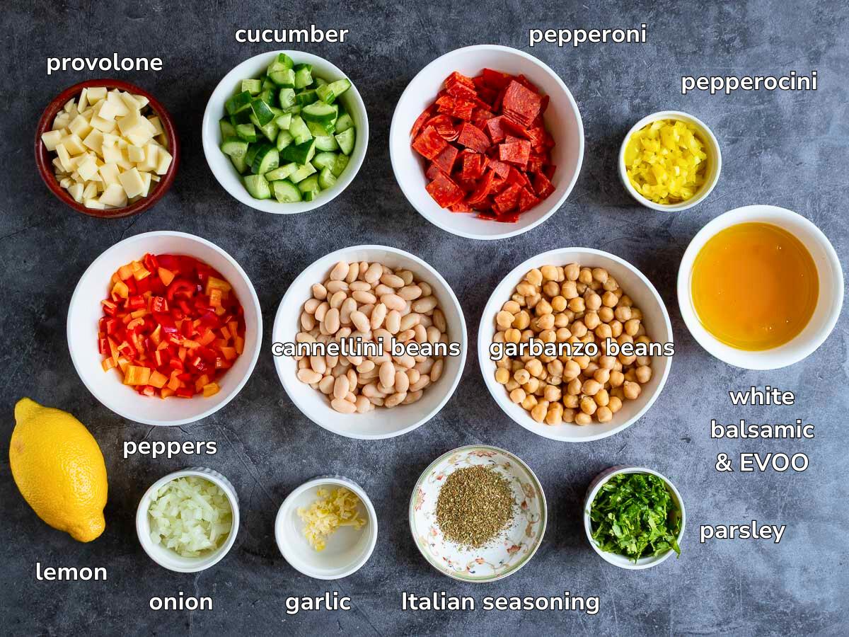 Ingredients to make the zesty bean salad laid out in white dishes all chopped and ready to go on a gray table. 
