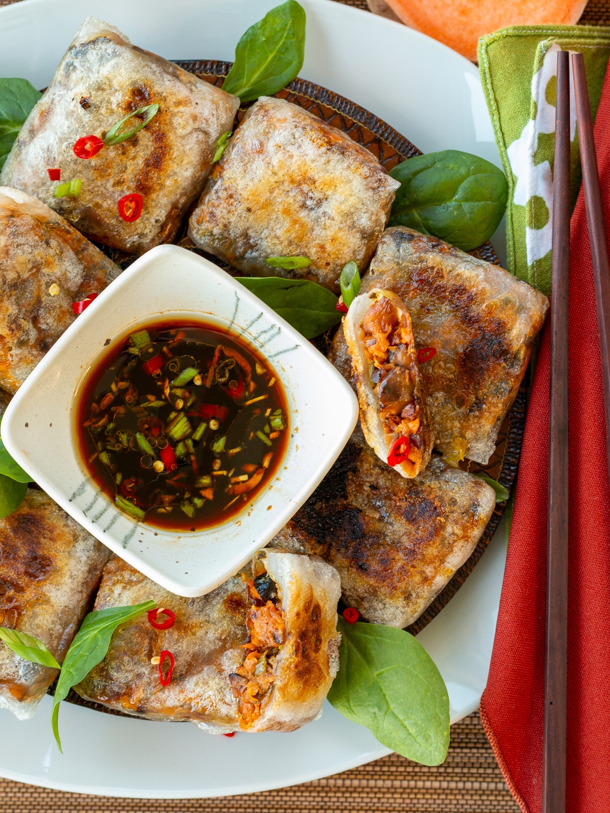Pan fried rice paper dumplings on a white plate with dipping sauce and chopsticks. 