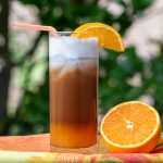 Outside sunny shot of iced bumblebee coffee garnished with oranges.
