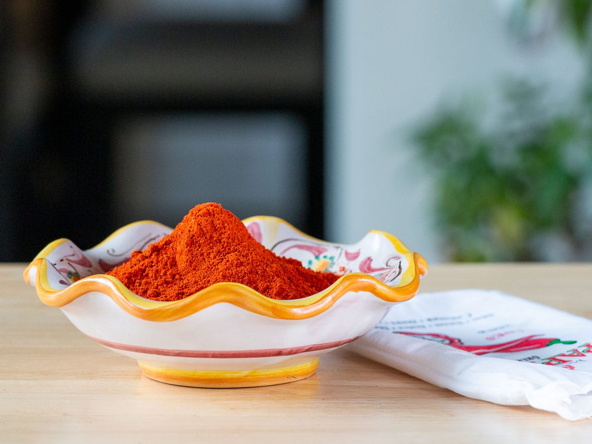 Bright red orange Hungarian sweet paprika in a white and yellow dish.