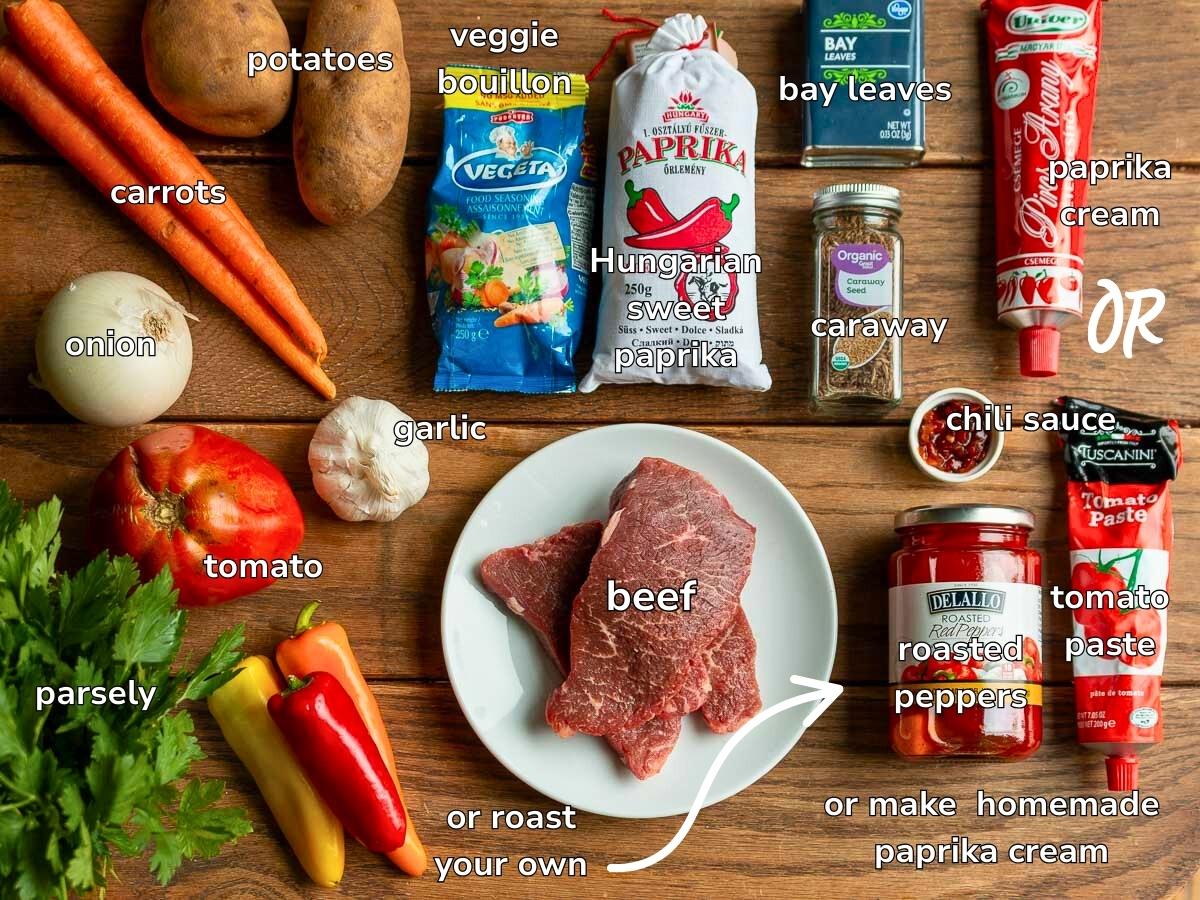 Ingredients to make Hungarian Goulash soup on a wooden board and also items to make homemade paprika cream from scratch. 