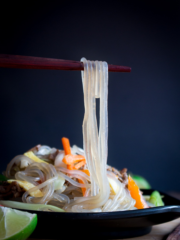 Bite shot holding noodles in chopsticks.