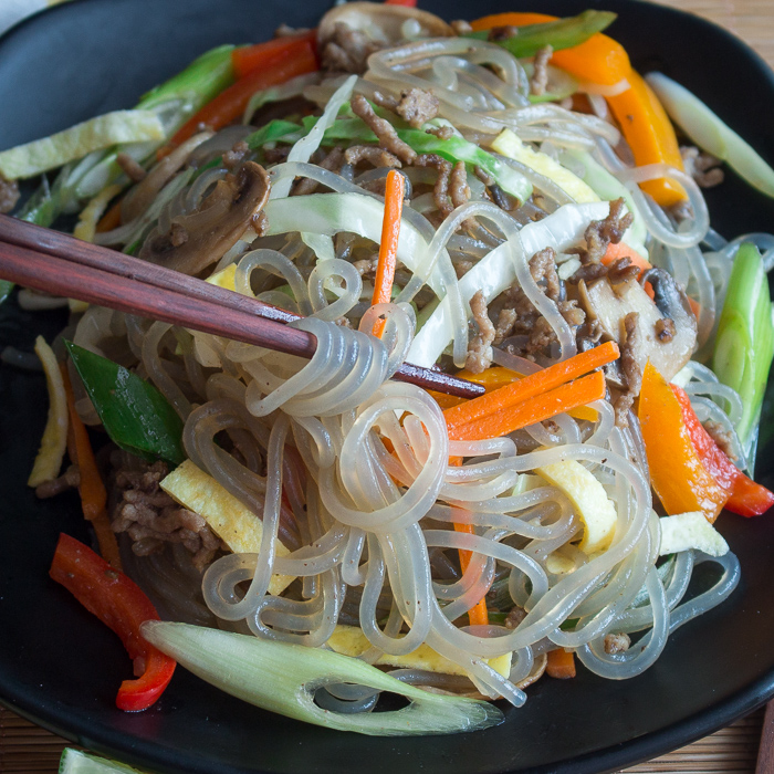 Twirling up the vegetables, noodles and ground beef on chopsticks. 
