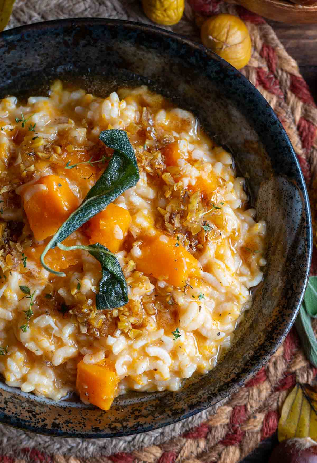 Top down shot of the completed pumpkin risotto with fried sage leaves and chestnut brown butter sauce.