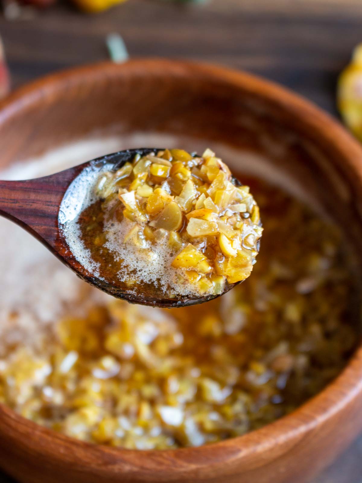 Scoop of brown butter sage and chestnut sauce in a wooden spoon.