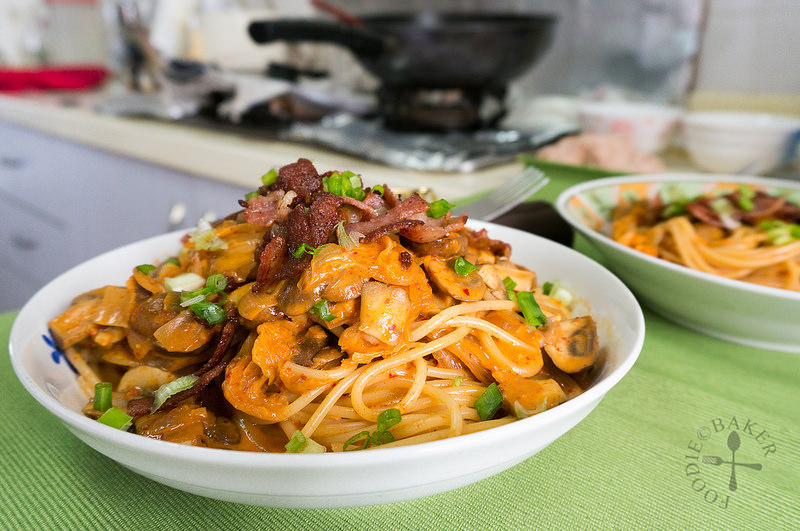 Korean pasta in a white bowl with lots of bacon.
