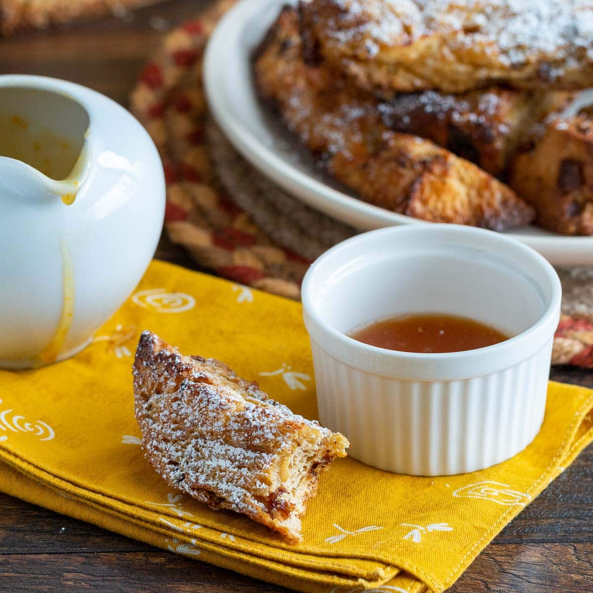 Bite of panettone French toast with a side of maple bourbon syrup.