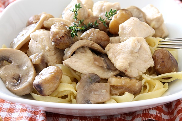 Chicken Breasts with Chestnuts and Mushrooms in a shite dish over a plaid red and white napkin.