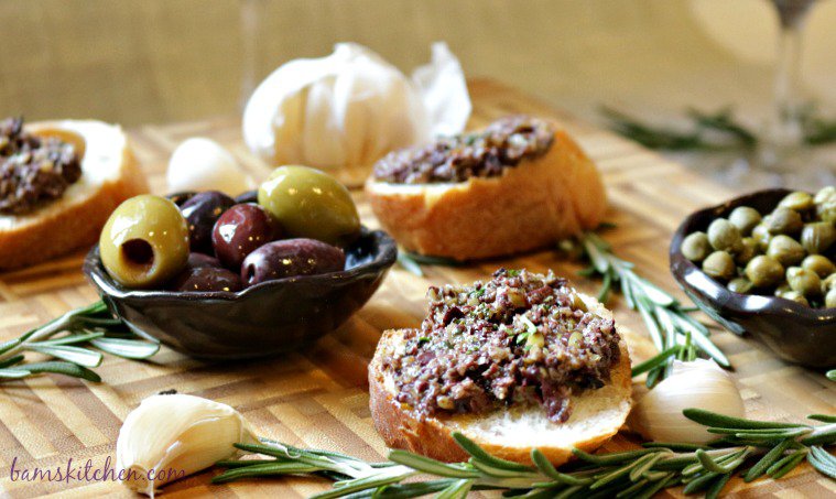 Pitted olives and capers on a wooden board.