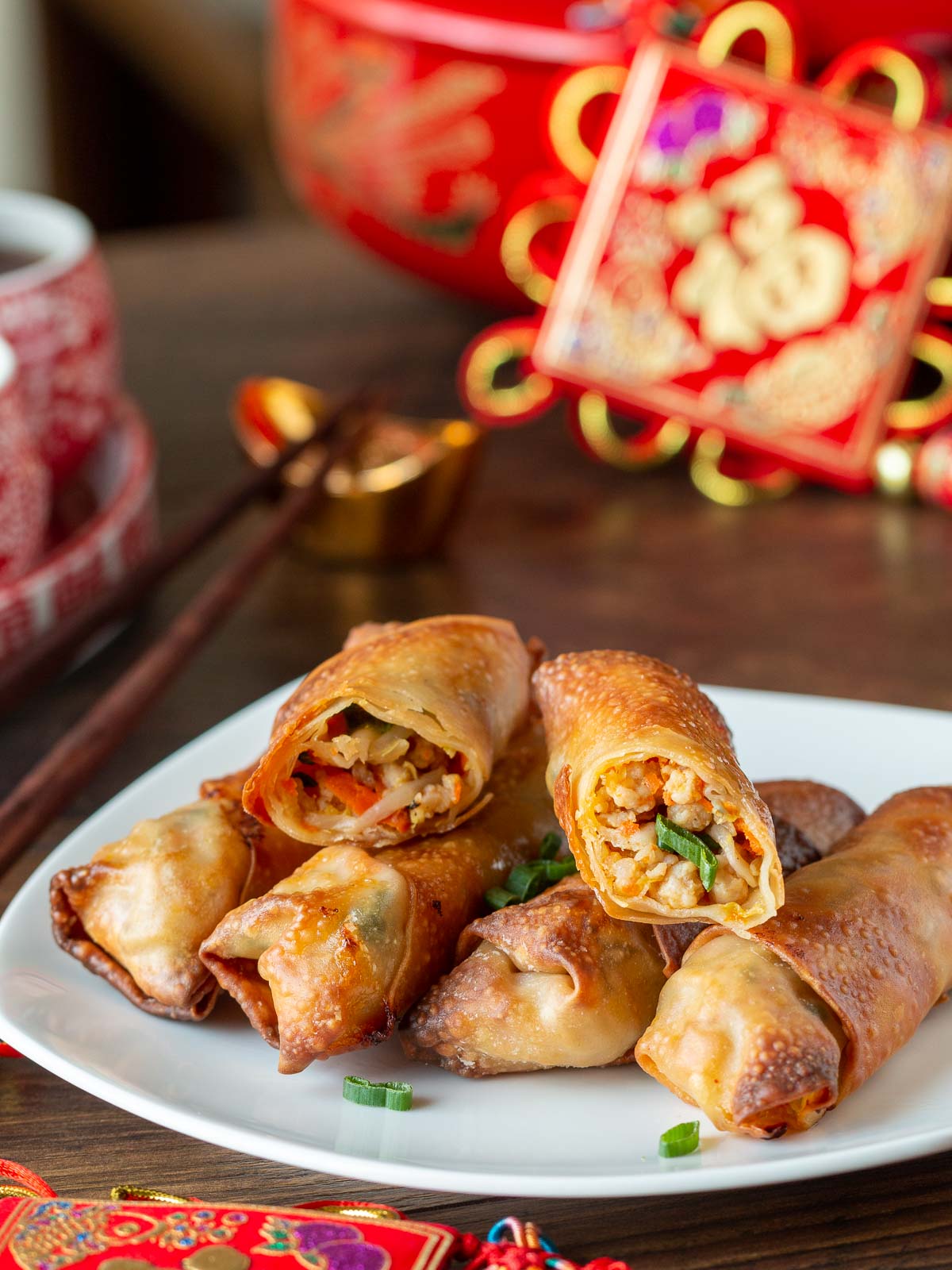 Air Fryer spring rolls on a white plate golden brown on a white plate with one cut in half and tea in the background.