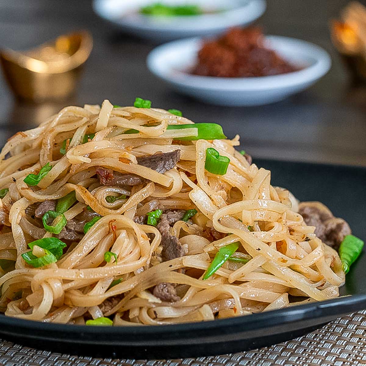 Stir Fried Beef and XO Noodles on a black plate.