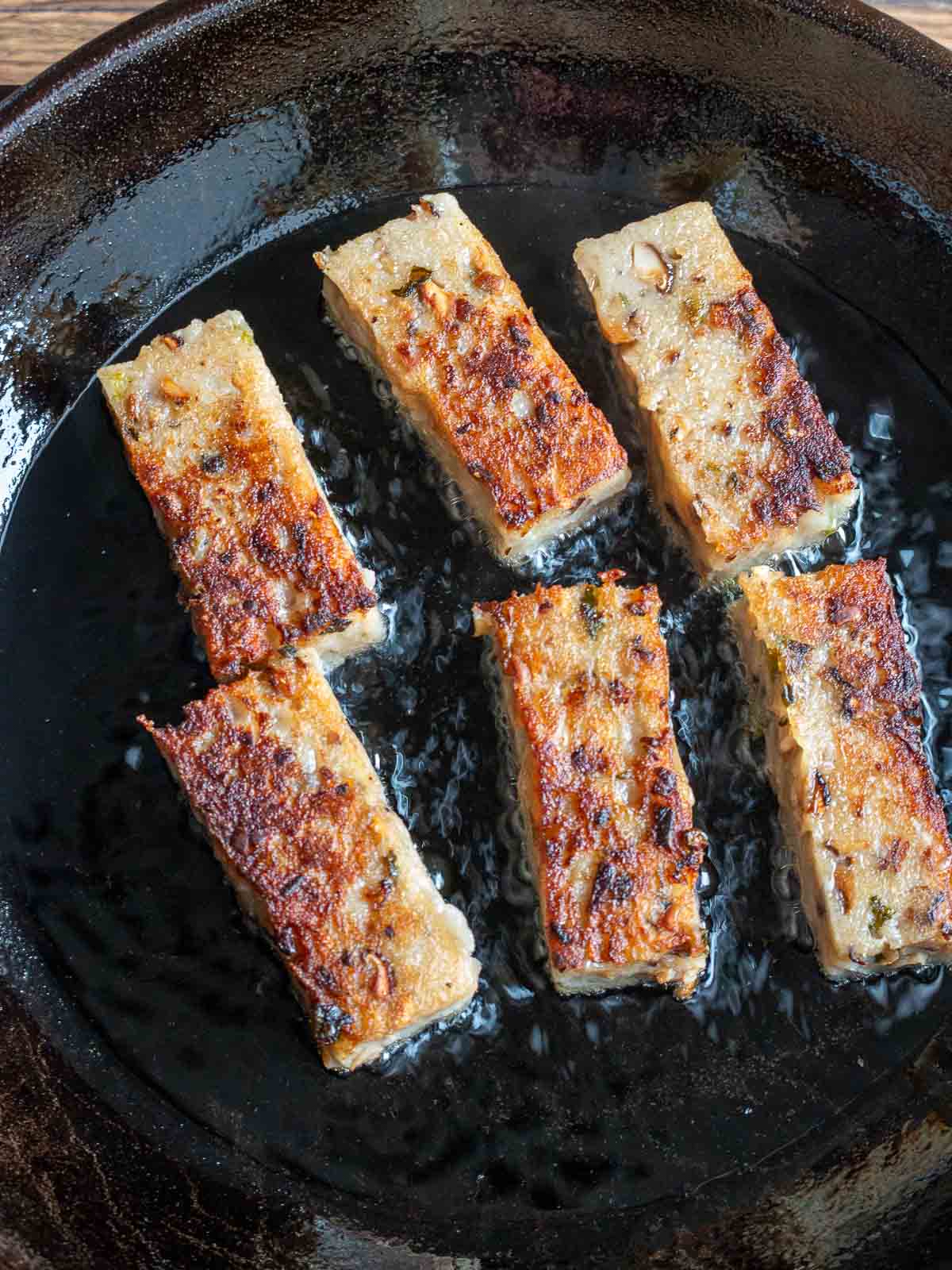 Lo Bak Go slices pan frying in an iron skillet.