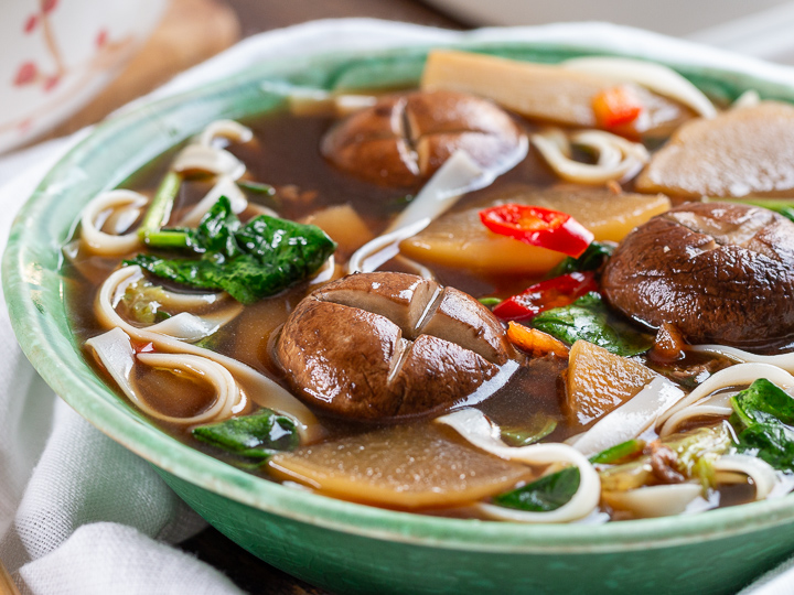 Mushrooms, daikon and noodles in a delicious deep broth in a green antique bowl.