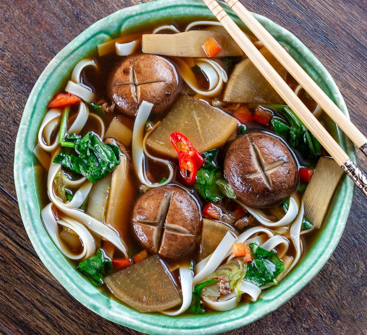 Delicious top down photo of Chinese Beef Noodle Soup Recipe in a green bowl with chopsticks.