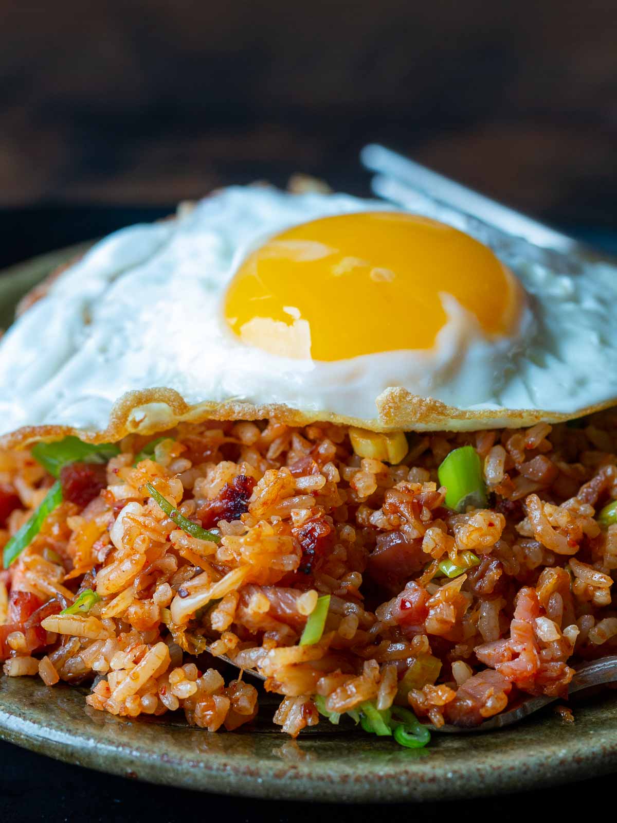 Close up a a perfectly cooked fried egg on top of crispy fried rice.
