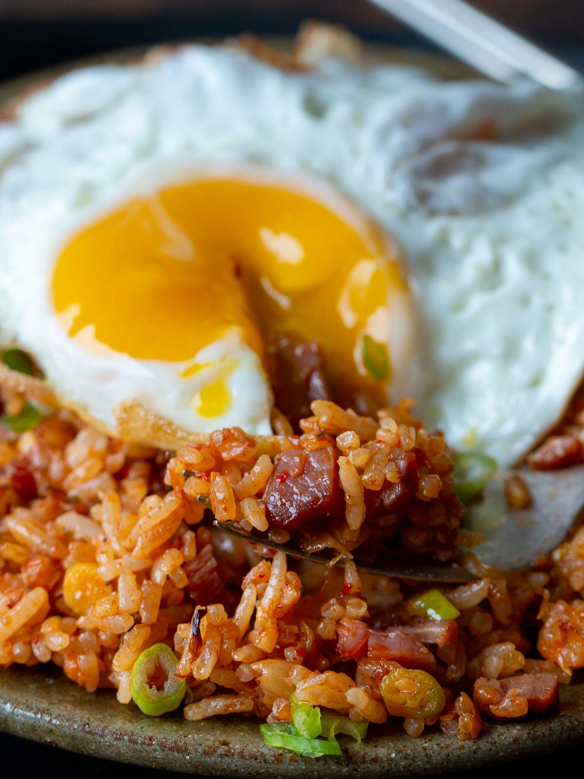 The bite shot with the runny Korean fried egg cut into and a fork full of rice. 