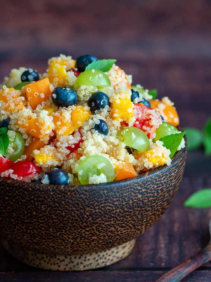 Lucious bright fruits with quinoa in a dark bowl with a brown background. 