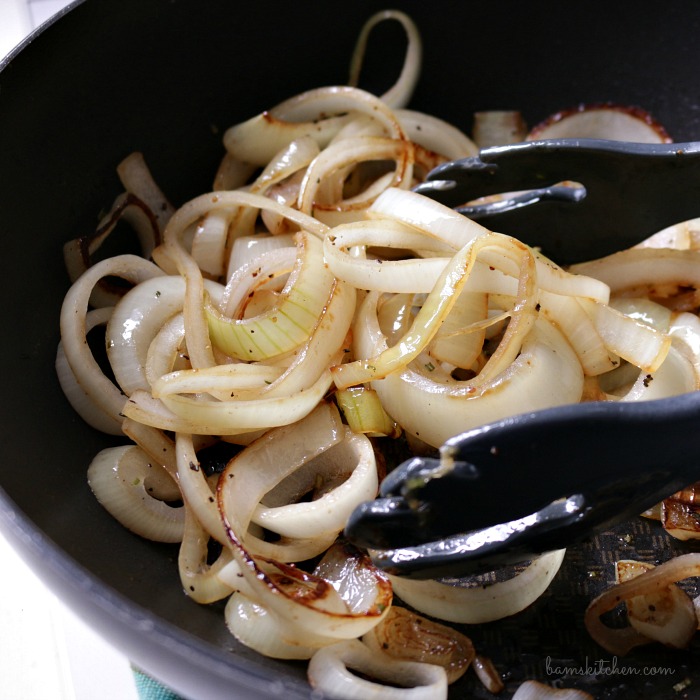 Stir frying onions in a black pan.