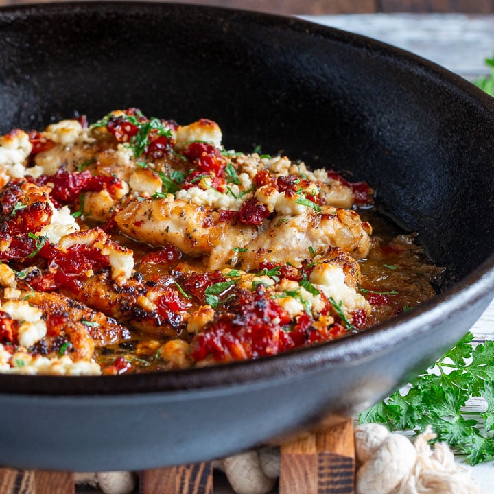 Close up of a cast iron skillet with the baked feta chicken inside.