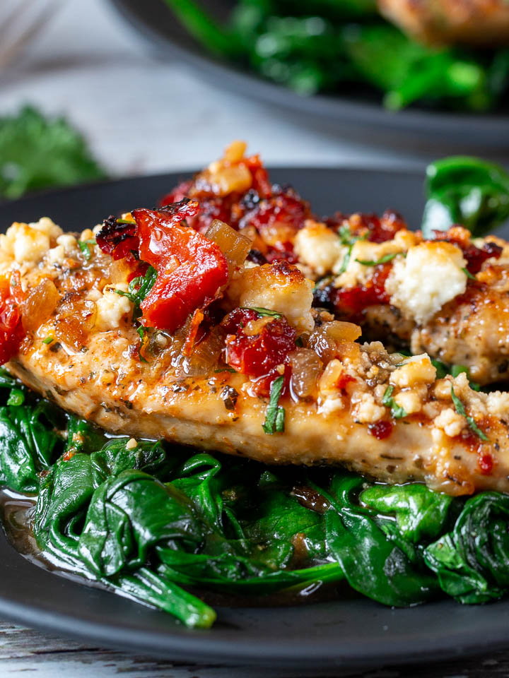 Greek feta chicken with sun-dried tomatoes over a bed of spinach.