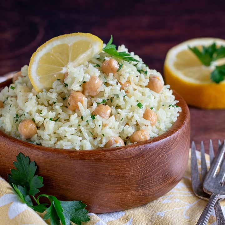 2 wooden bowls of lemon pepper rice garnished with a fresh lemon wedge.